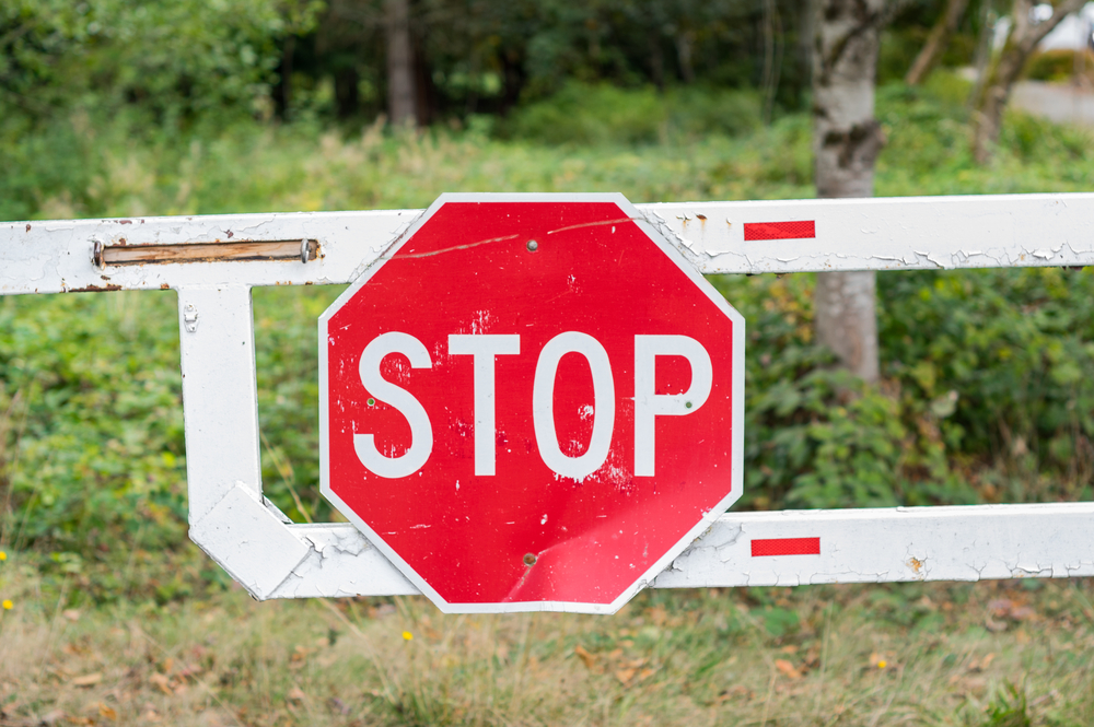Red stop sign on a gate over a closed driveway