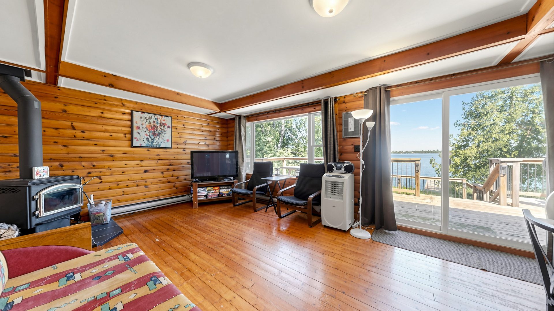 A wood living area with floor-to-ceiling windows facing the lake