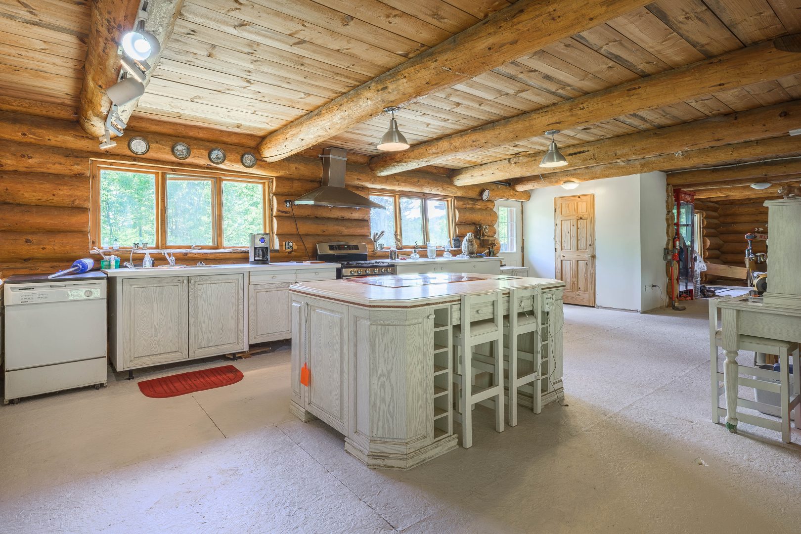 A spacious kitchen in a log cabin with a white wood island and white cabinetry