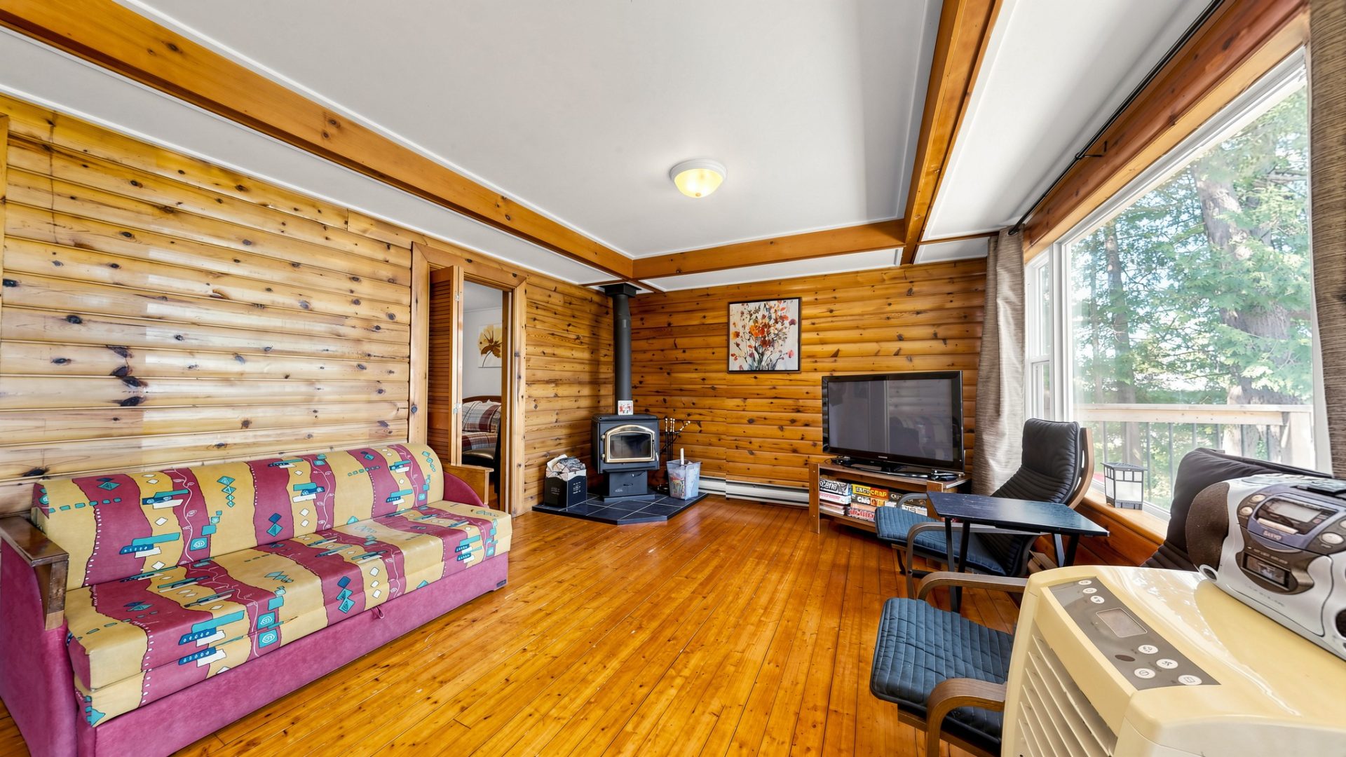 A wood living room with a red plaid couch and a wood stove