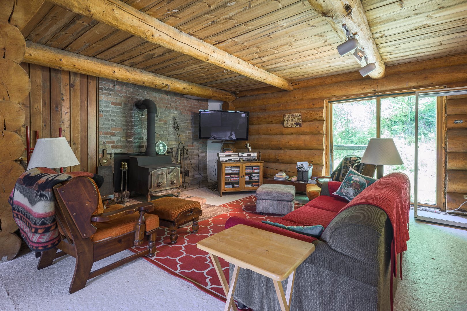 A grey couch and red couch faces a wood stove in a wood living room