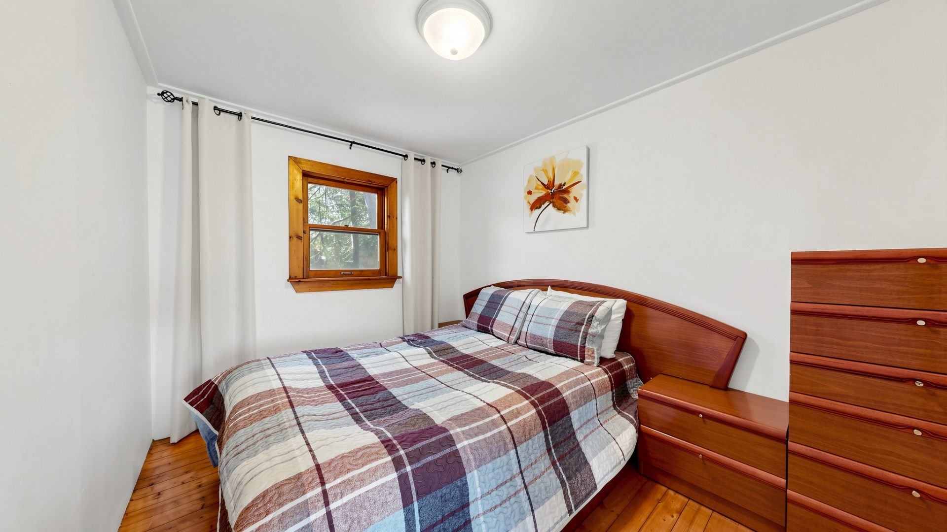 A wood bed with a plaid bedspread
