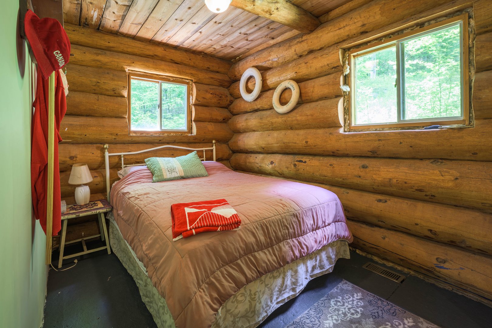 A bed with a pink cover in a wood cabin