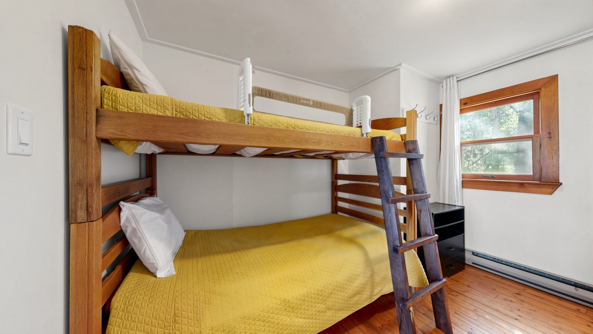 Wood bunk beds with yellow bedspreads in a white bedroom
