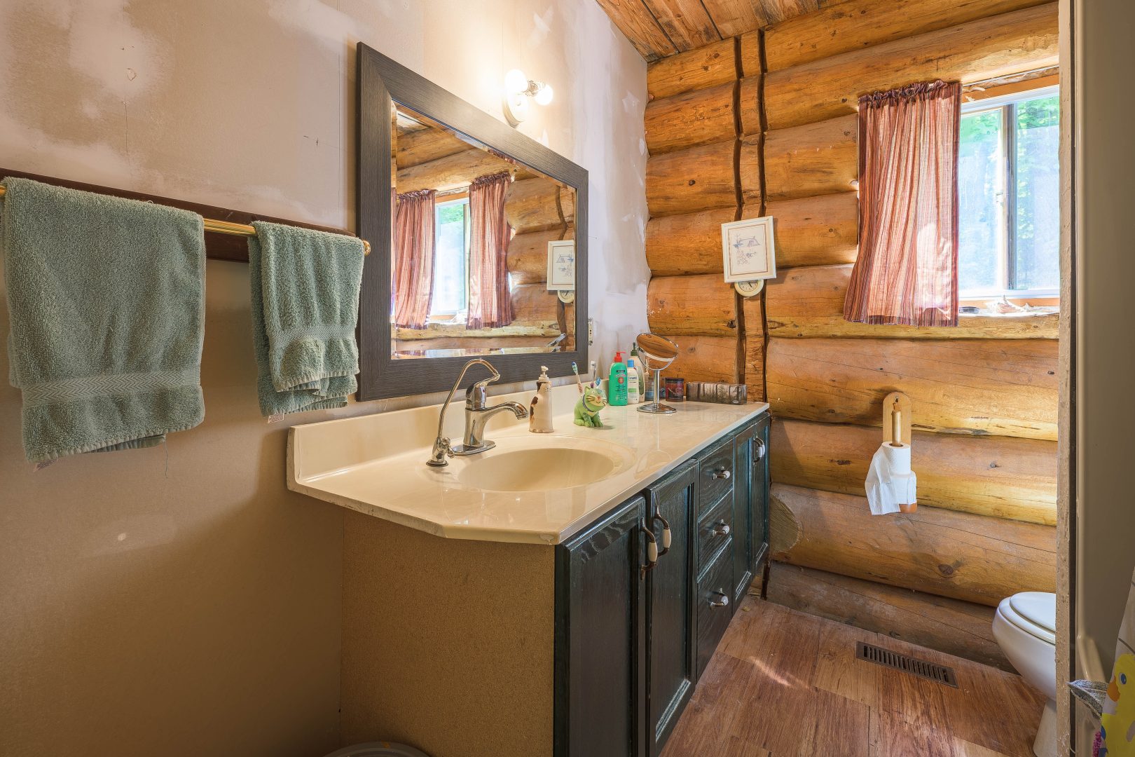 A vanity with a dark wood cabinet and a square mirror