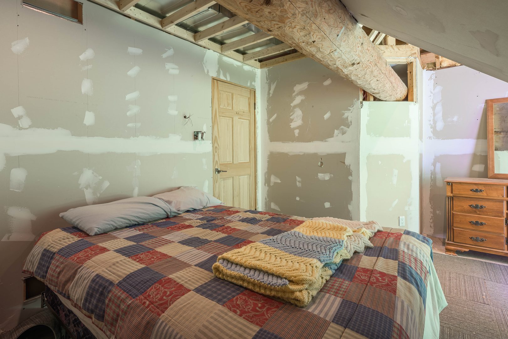 A quilted bed in an unfinished bedroom