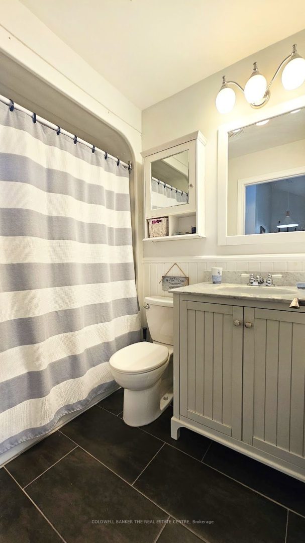 A white bathroom with a plaid shower curtain and grey vanity