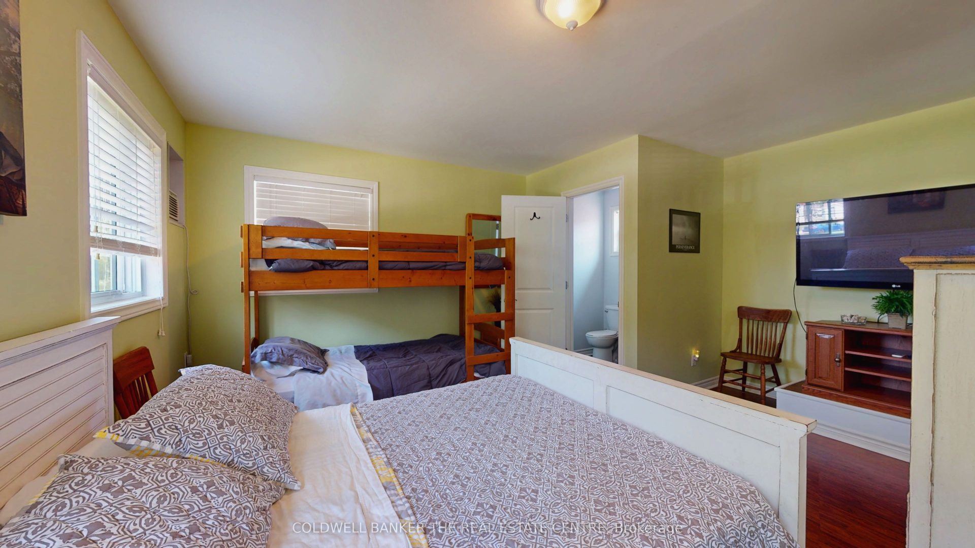 A light purple bed next to a wood bunk bed in a light green bedroom
