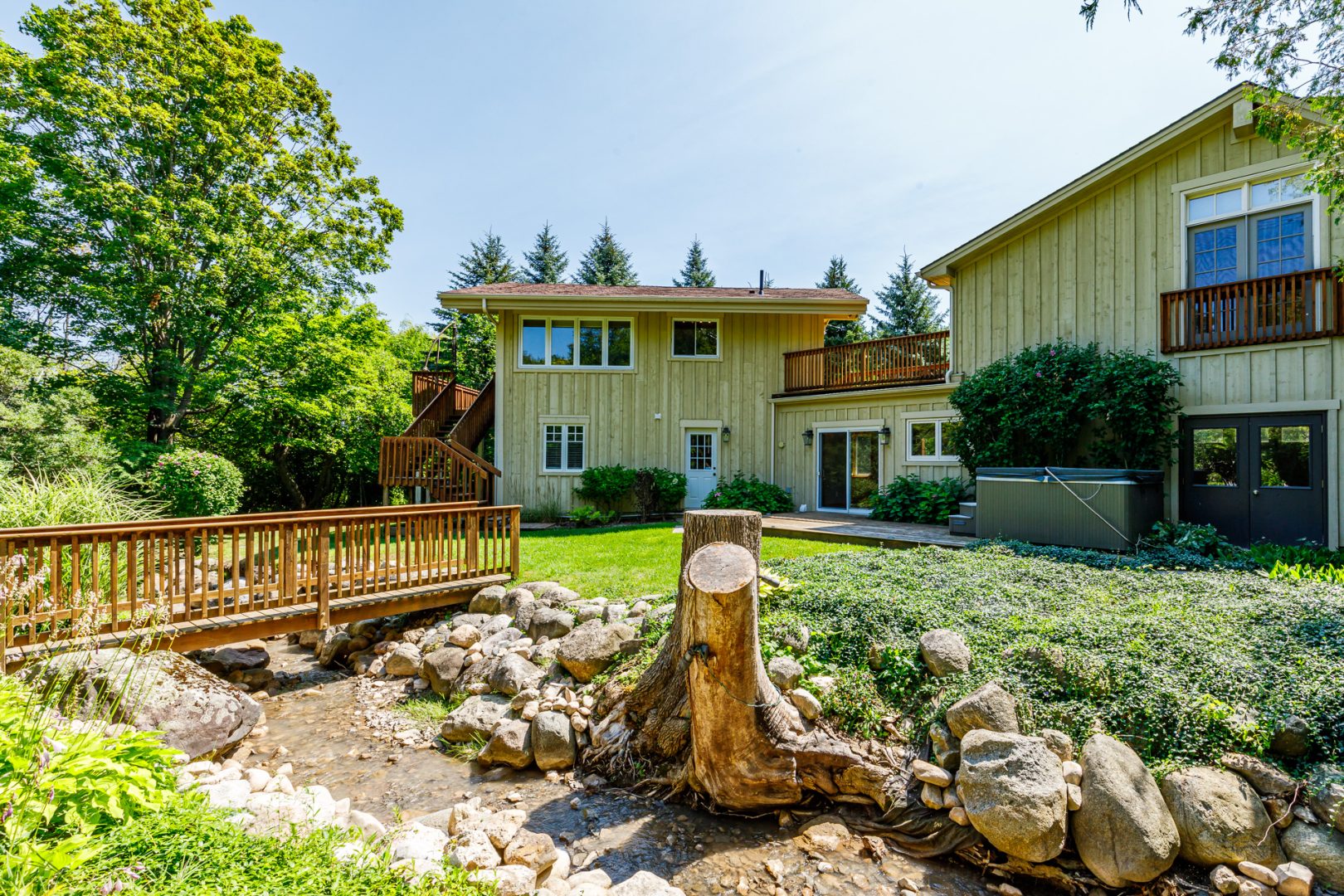 A light green clapboard cottage on a grassy property