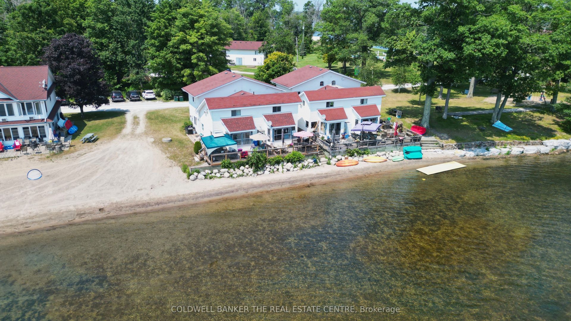 Two white cottages with red trim on a beach shoreline