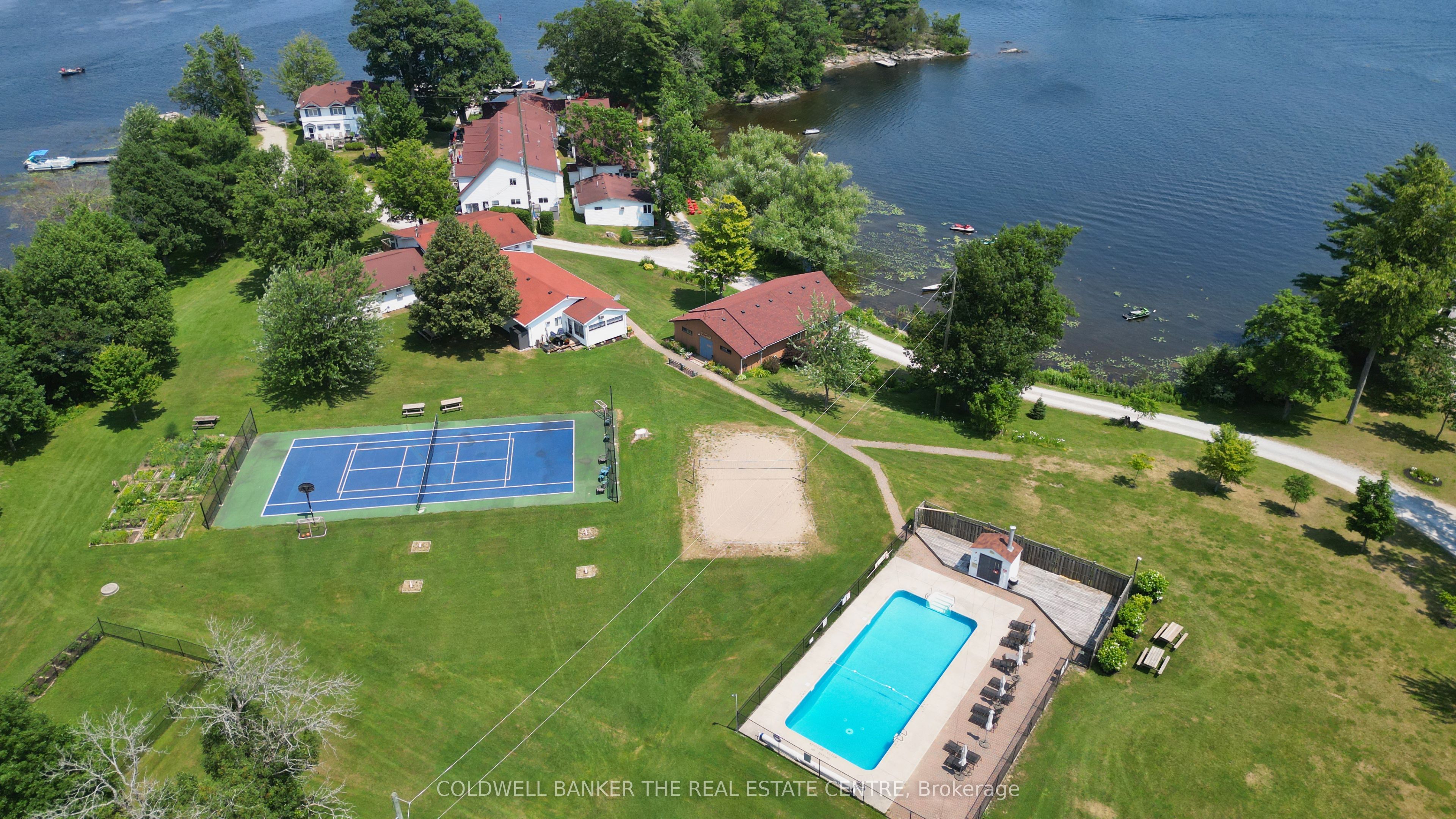 Aerial view of the cottage property with a pool, tennis court, and volleyball court