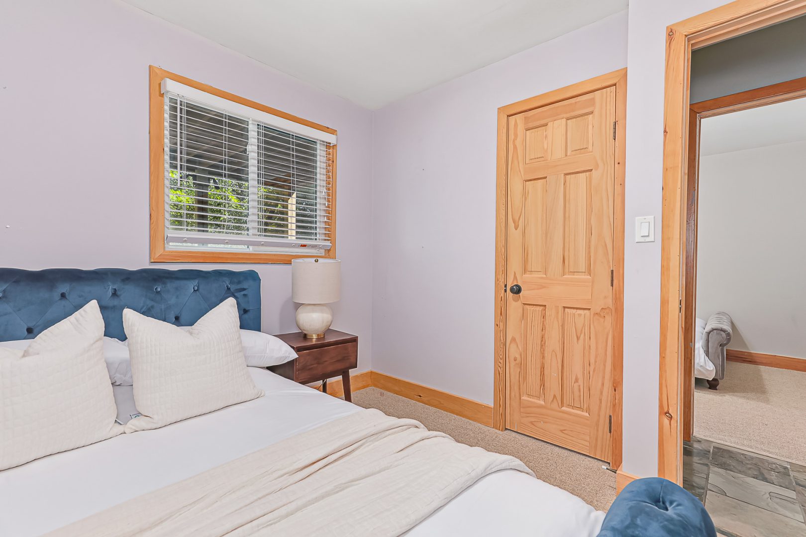 A white bed on a blue frame in a white bedroom