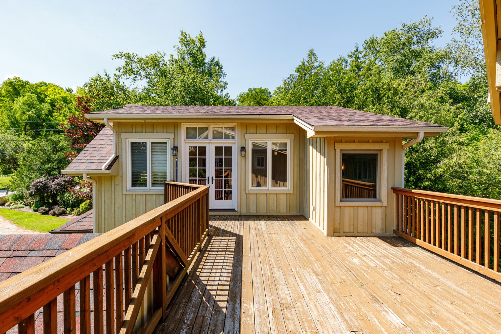 A wood deck outside a light green clapboard cottage