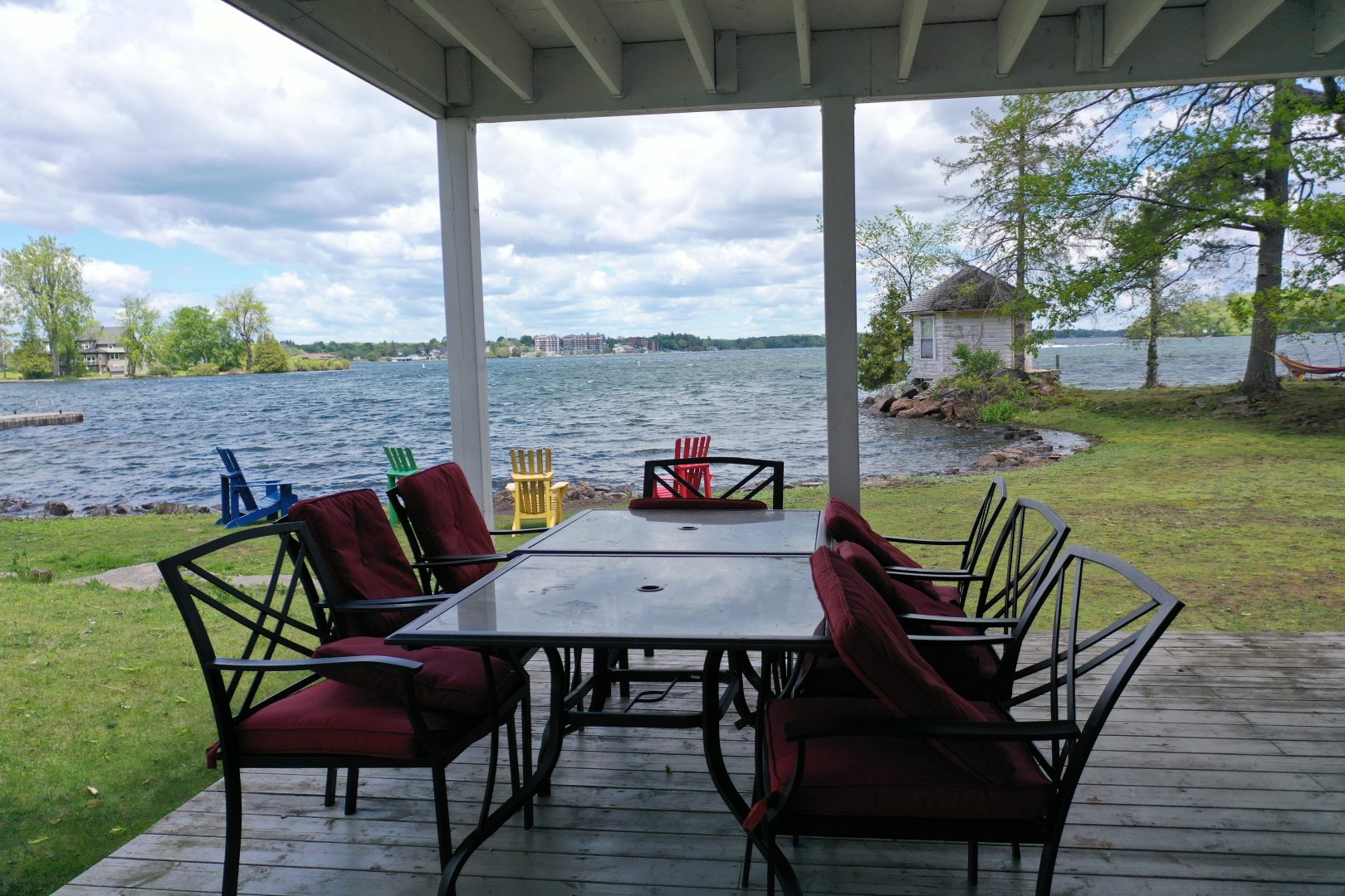 An outdoor patio set with red cushions looking out to the lake