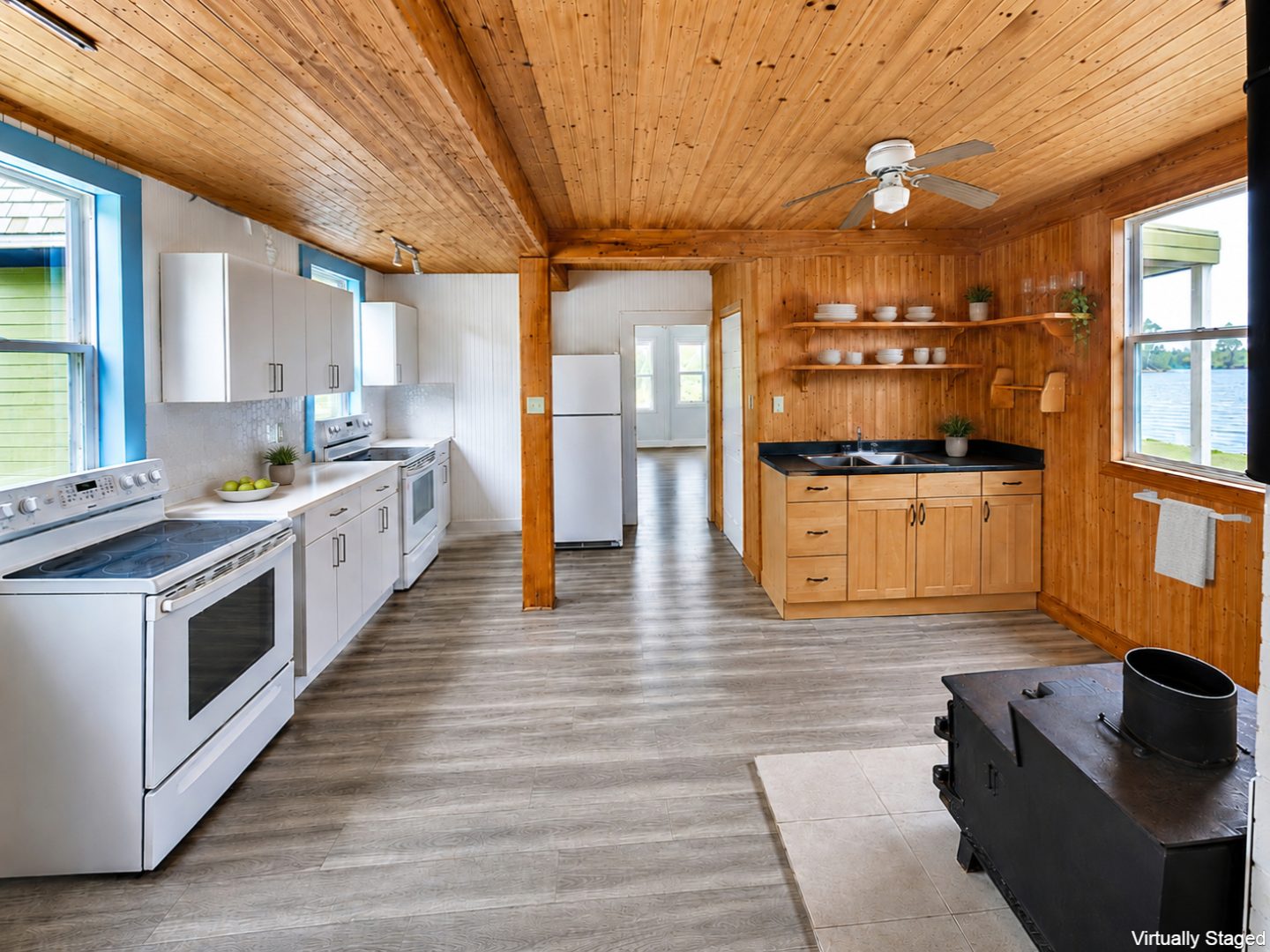 A wall of white cabinetry and appliances in a wood-paneled room