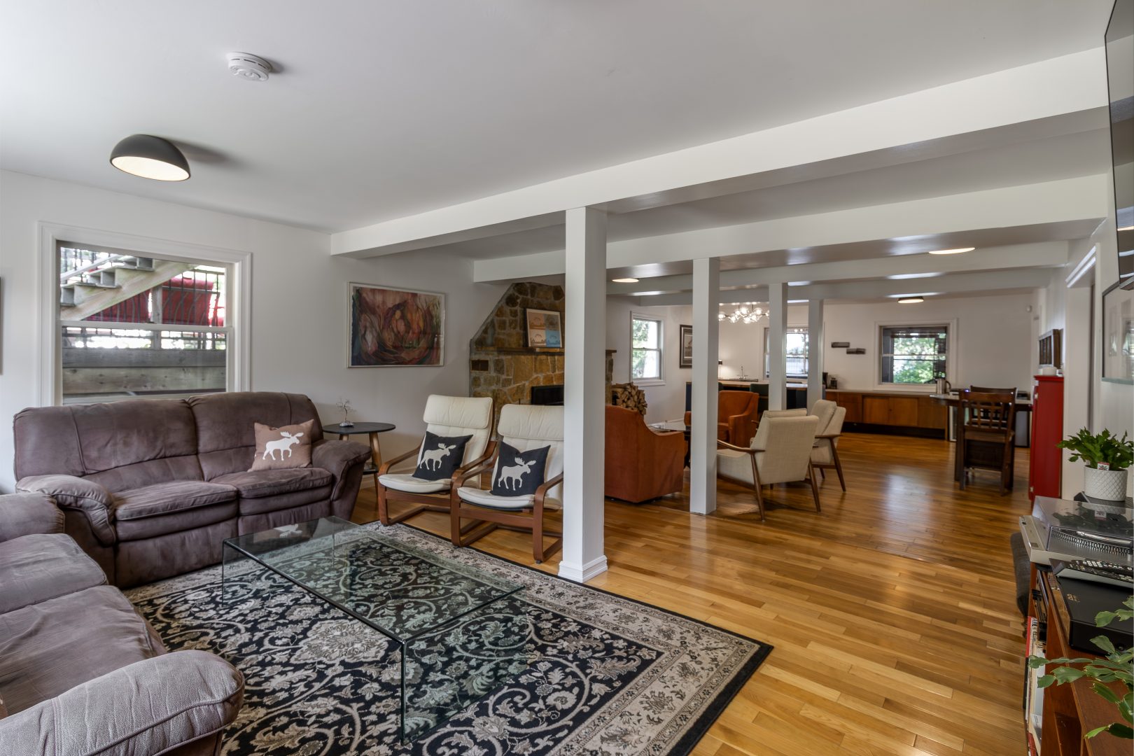 A spacious living room with a large patterned carpet and multiple sitting areas