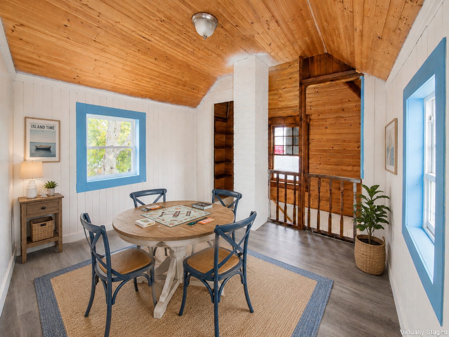 A small round wood table with blue chairs in a white room
