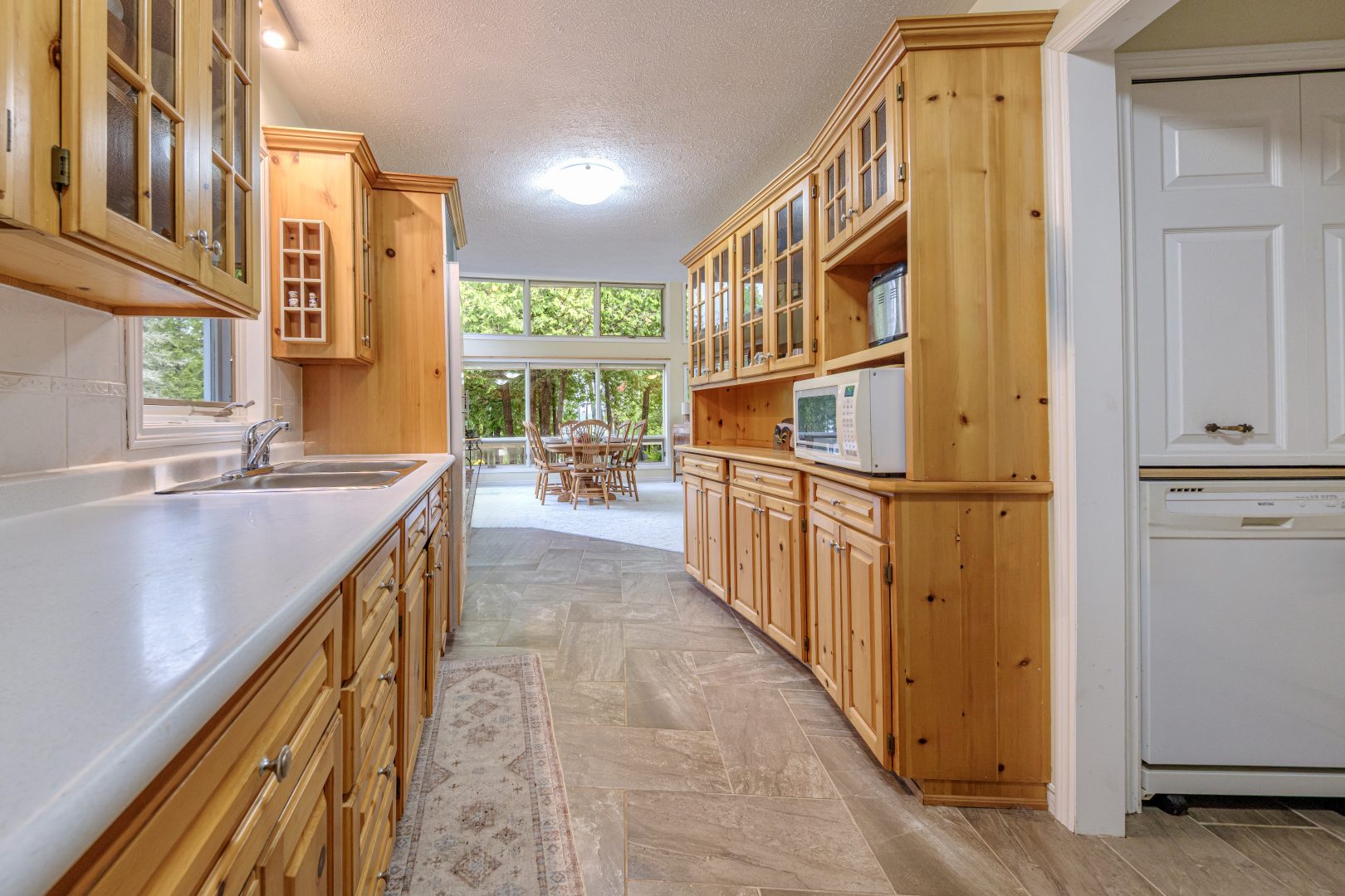 A narrow kitchen with light brown wood cabinets