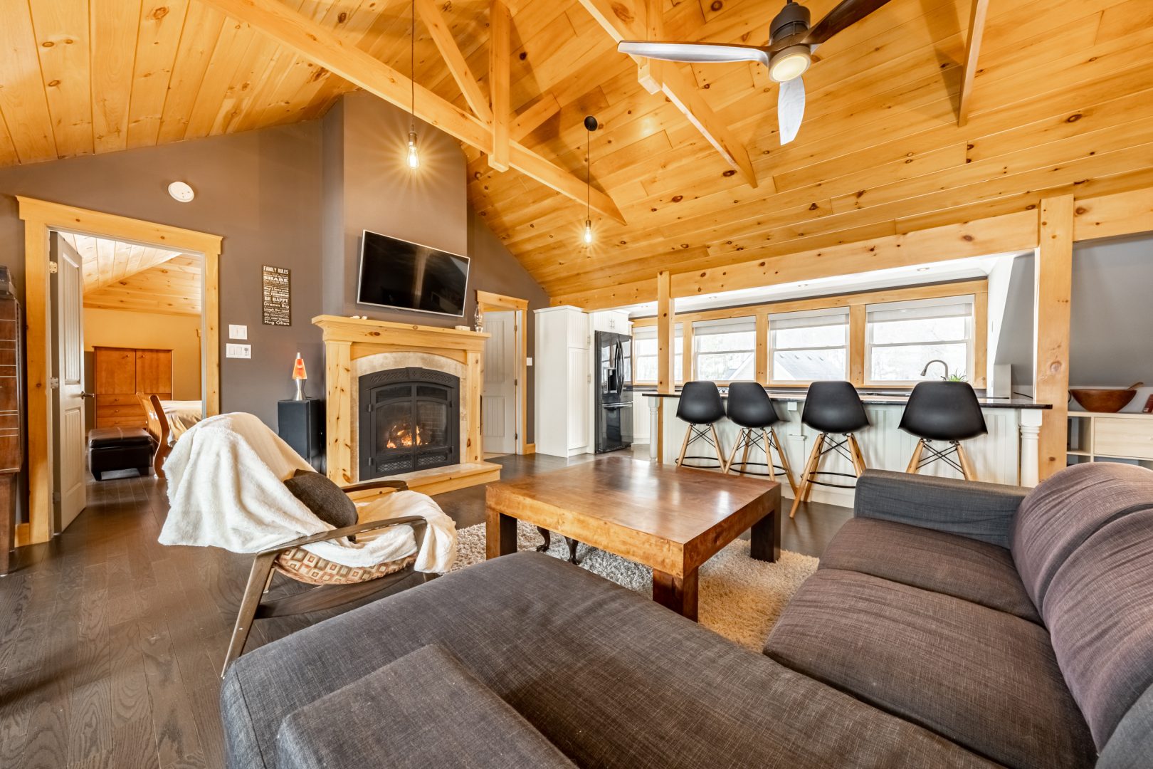 A spacious living room with a grey couch, stone fireplace and vaulted ceilings