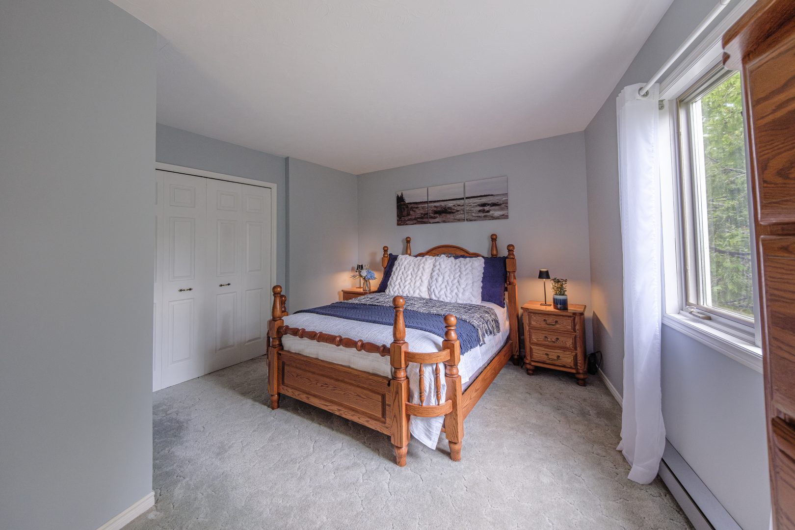 A white bed on a warm brown bed frame with a purple throw