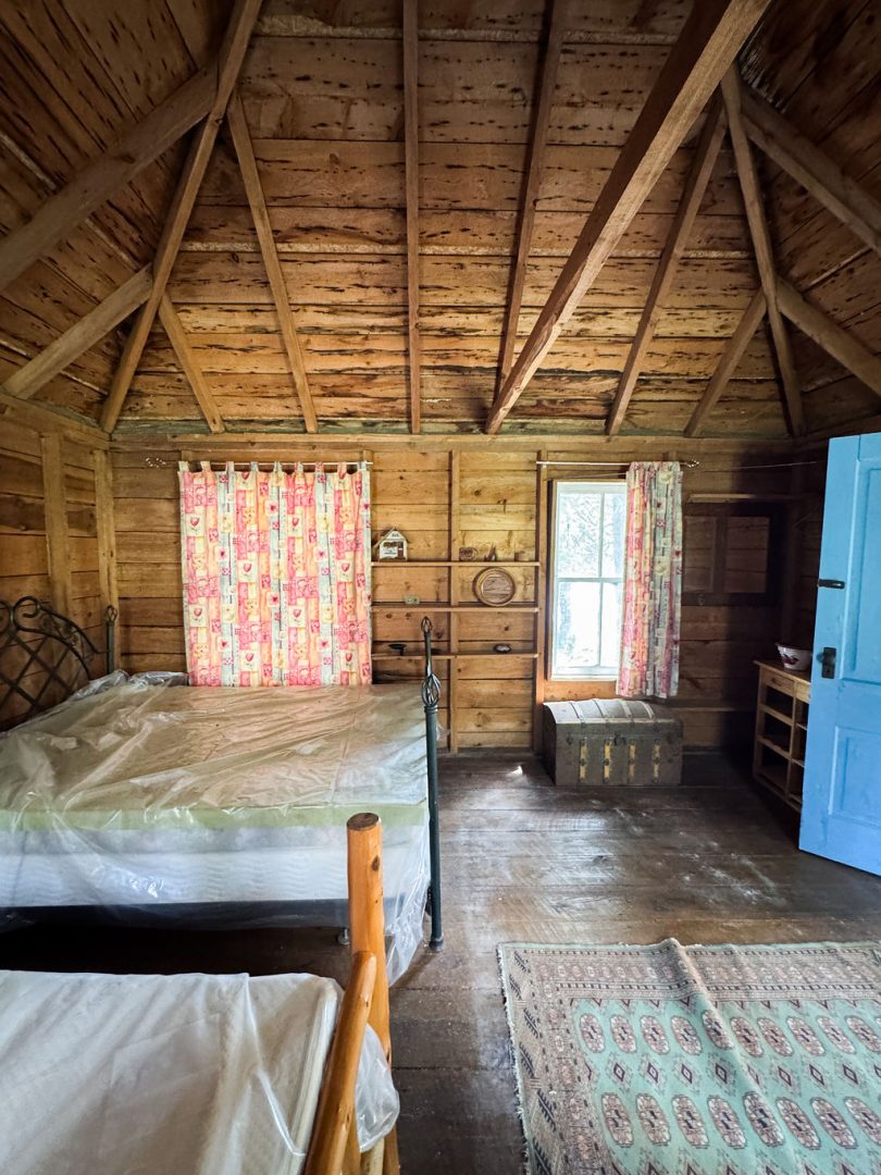 Two beds covered in plastic wraps in a wood cabin