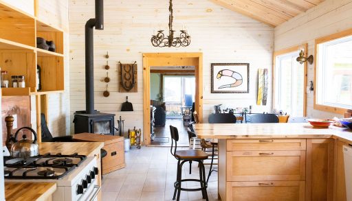 A shiplap kitchen with a wood island with seating and a black wood stove