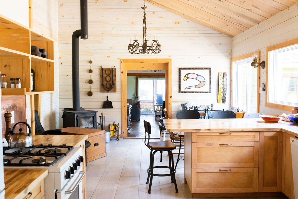 A shiplap kitchen with a wood island with seating and a black wood stove