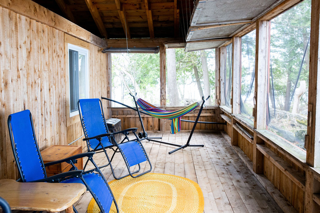 A screened-in porch with two blue lounge chairs