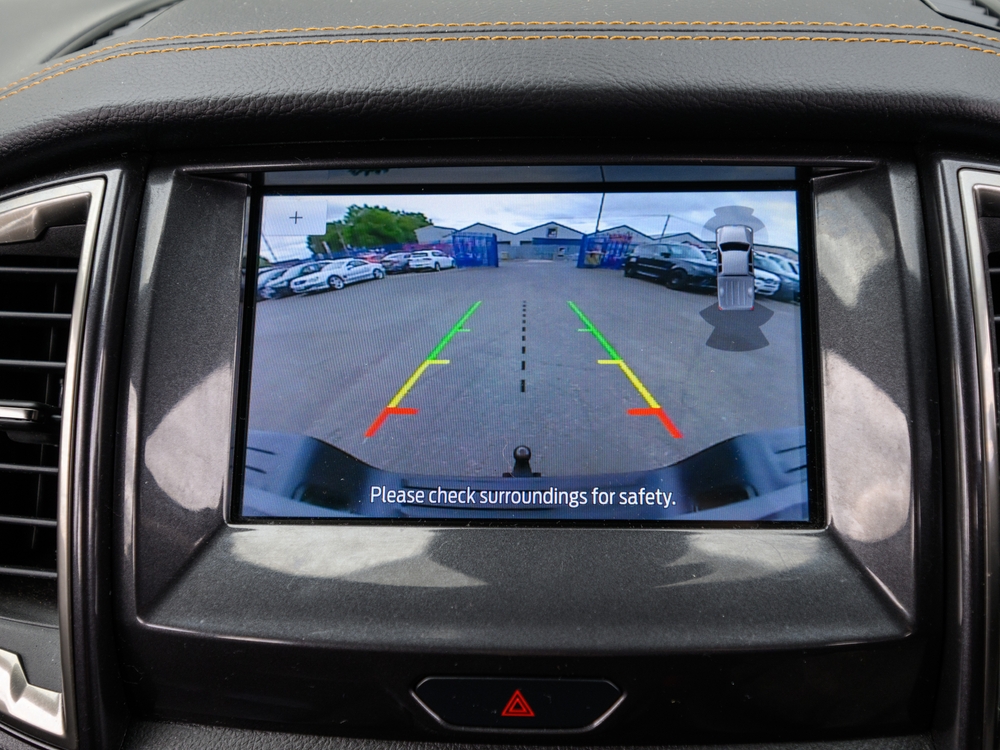 Modern cars infotainment screen displaying a live feed from the backup reverse camera, assisting the driver with safe parking and obstacle detection