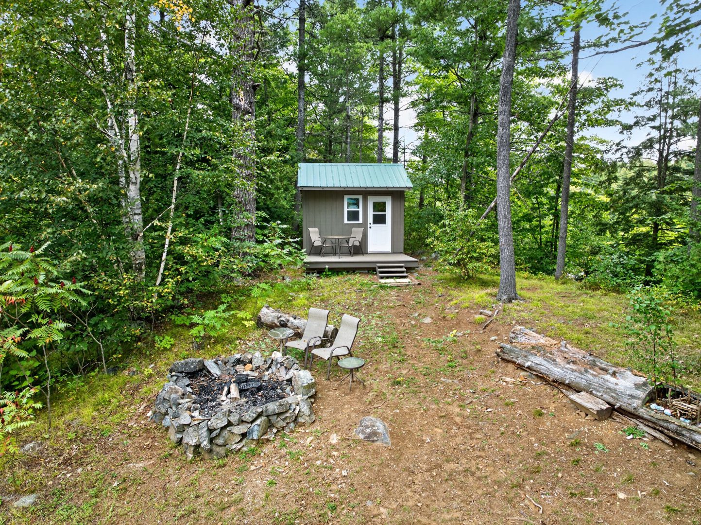 A small grey building on a forested property