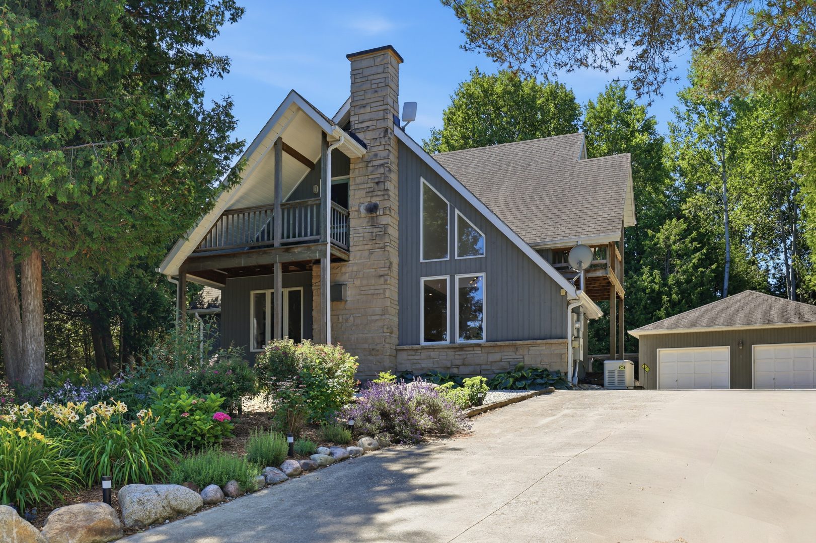 A grey A-frame cottage with a wide driveway