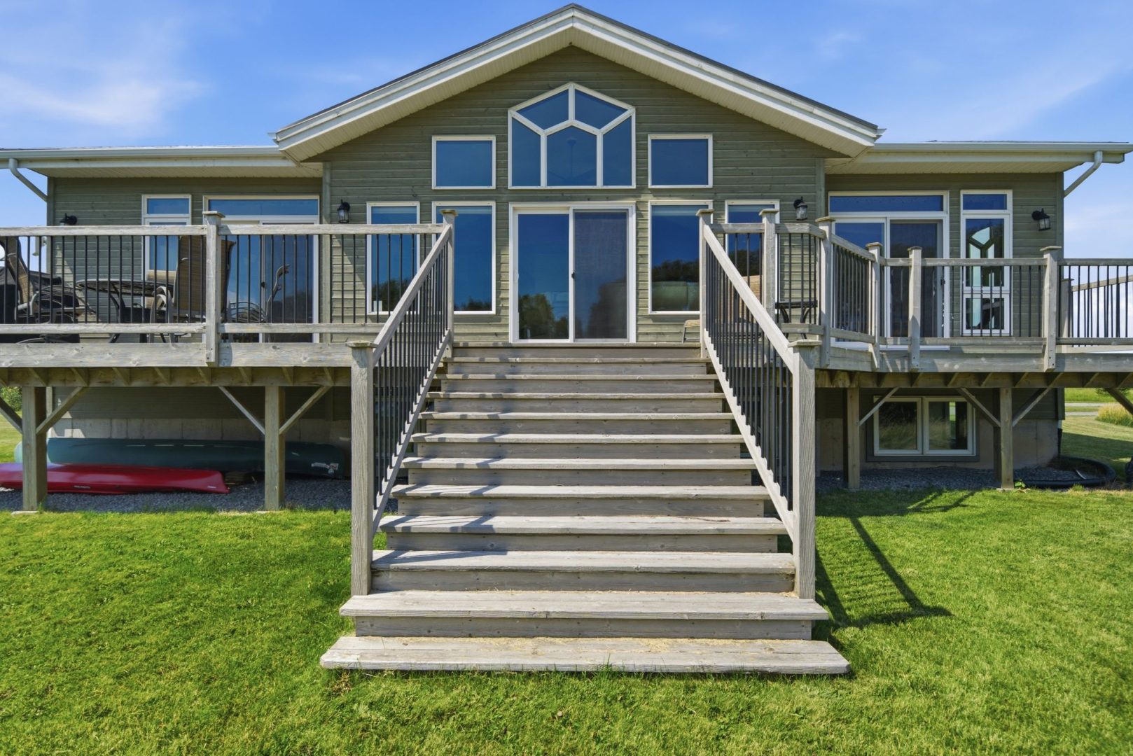 Wood stairs lead down from a green clapboard cottage with a deck