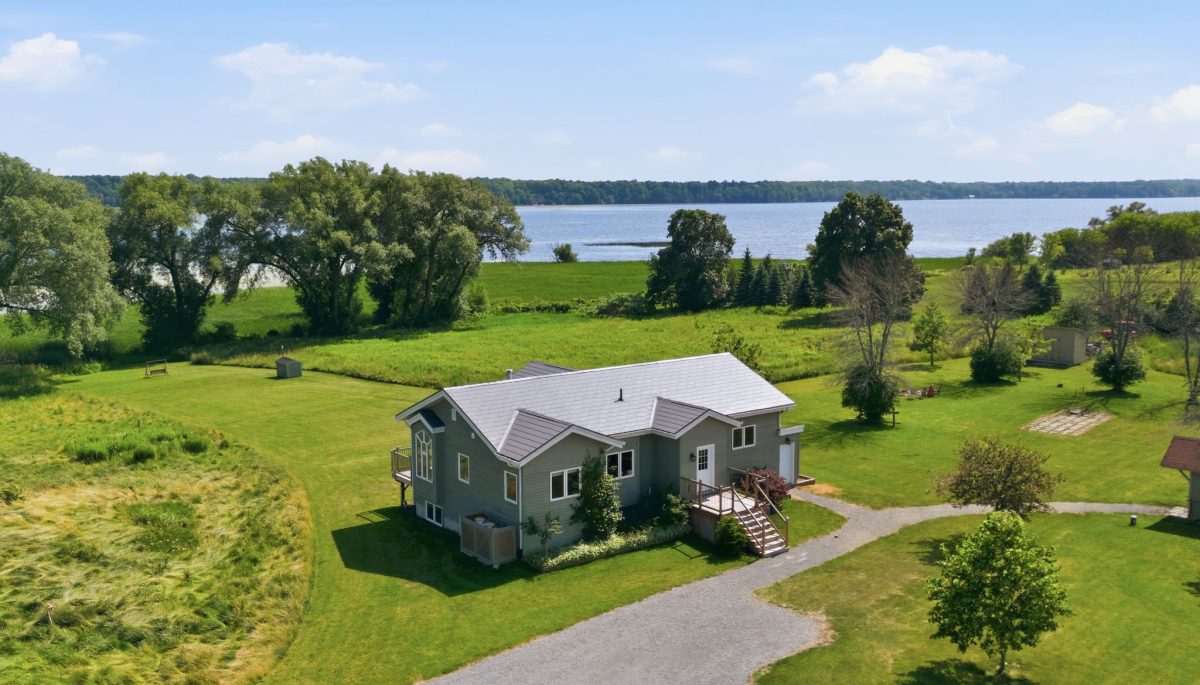 A green clapboard cottage on a sprawling grassy property