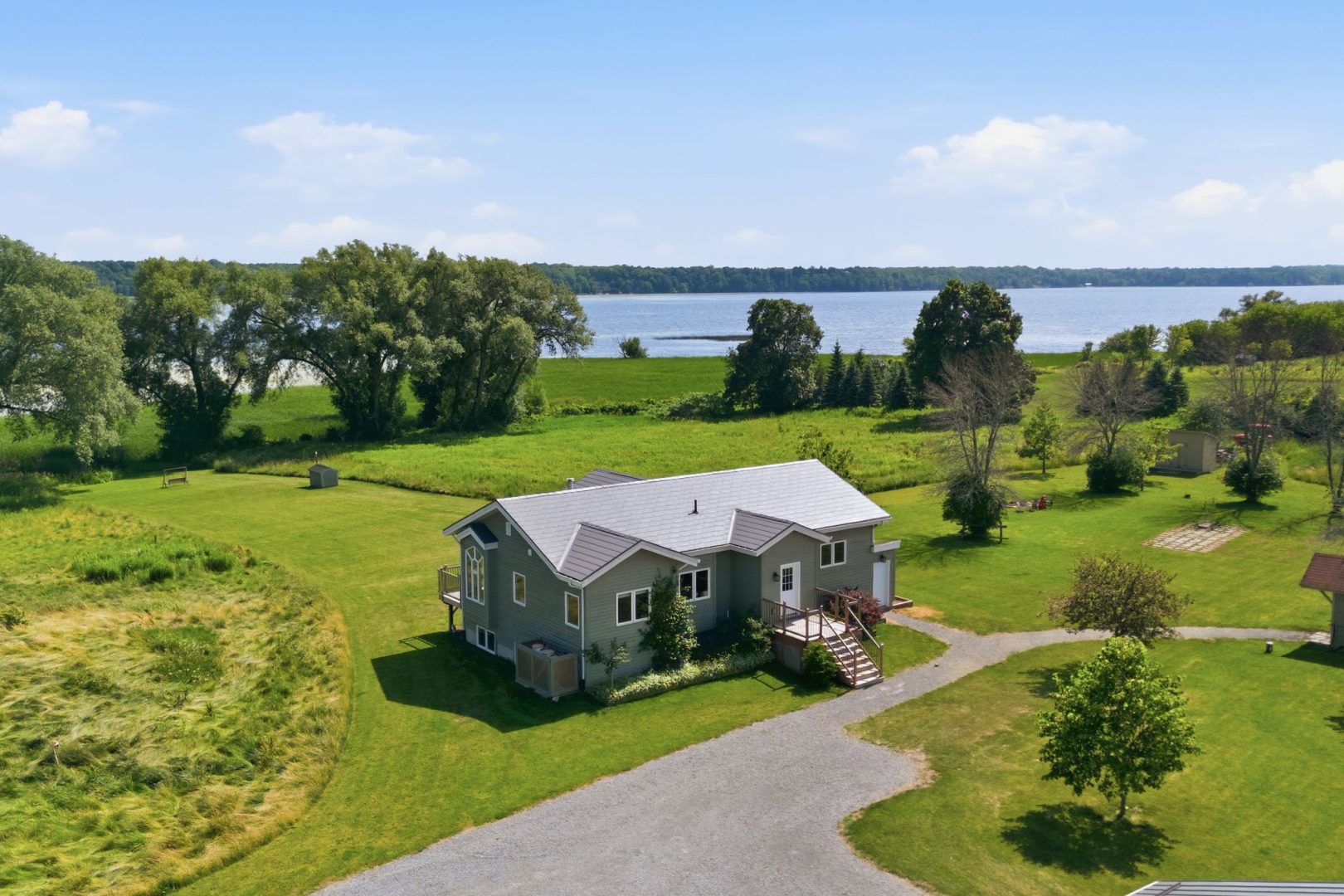 A green clapboard cottage on a sprawling grassy property
