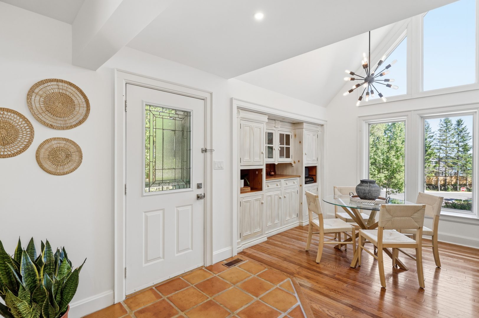 A bright entryway with a white front door and a small dining area to the right