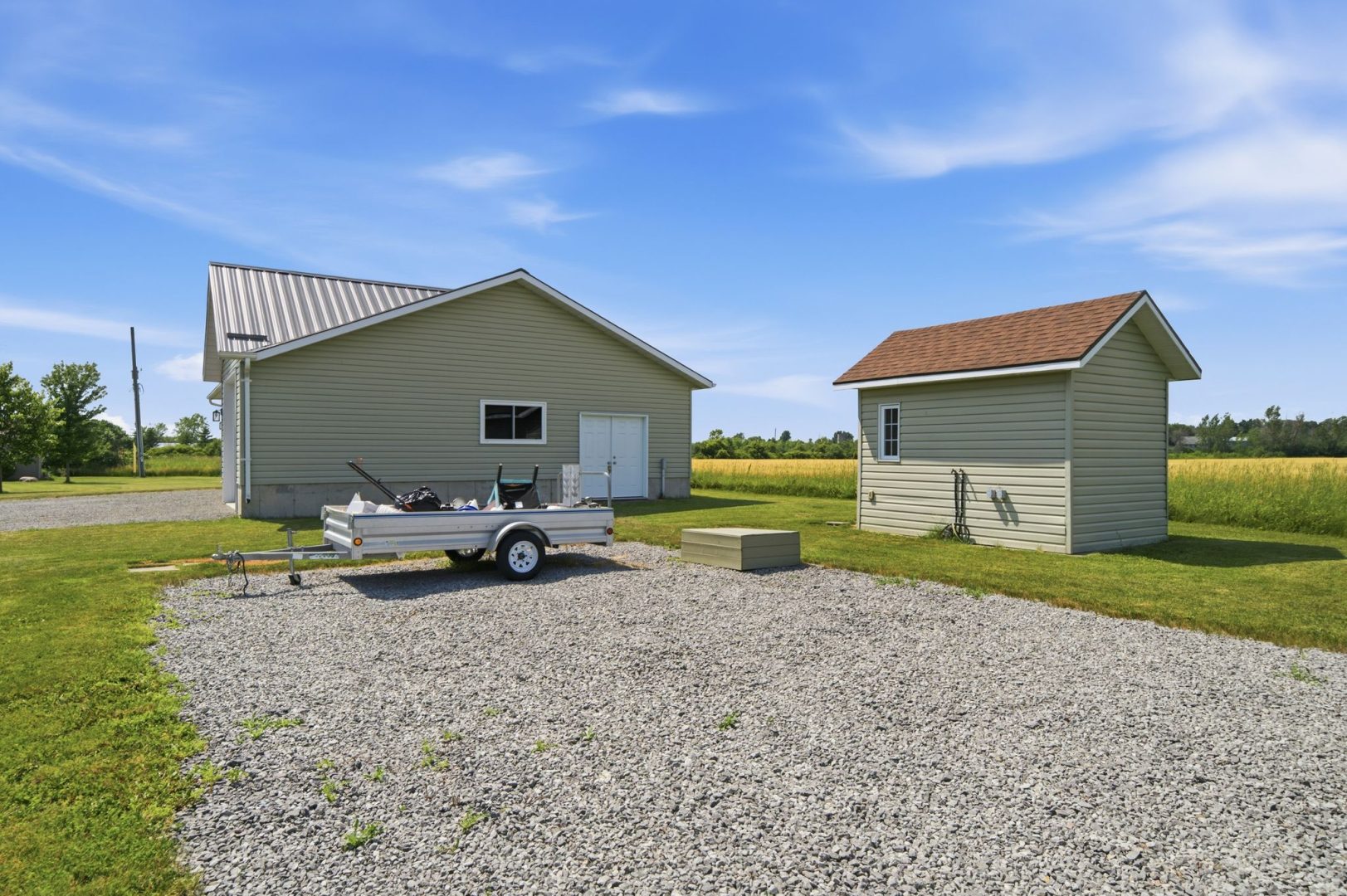 A painted green garage next to a green shed
