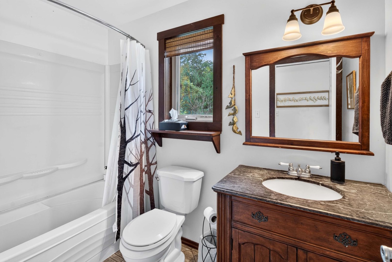 A white bathroom with a wood vanity and a wood-trimmed window