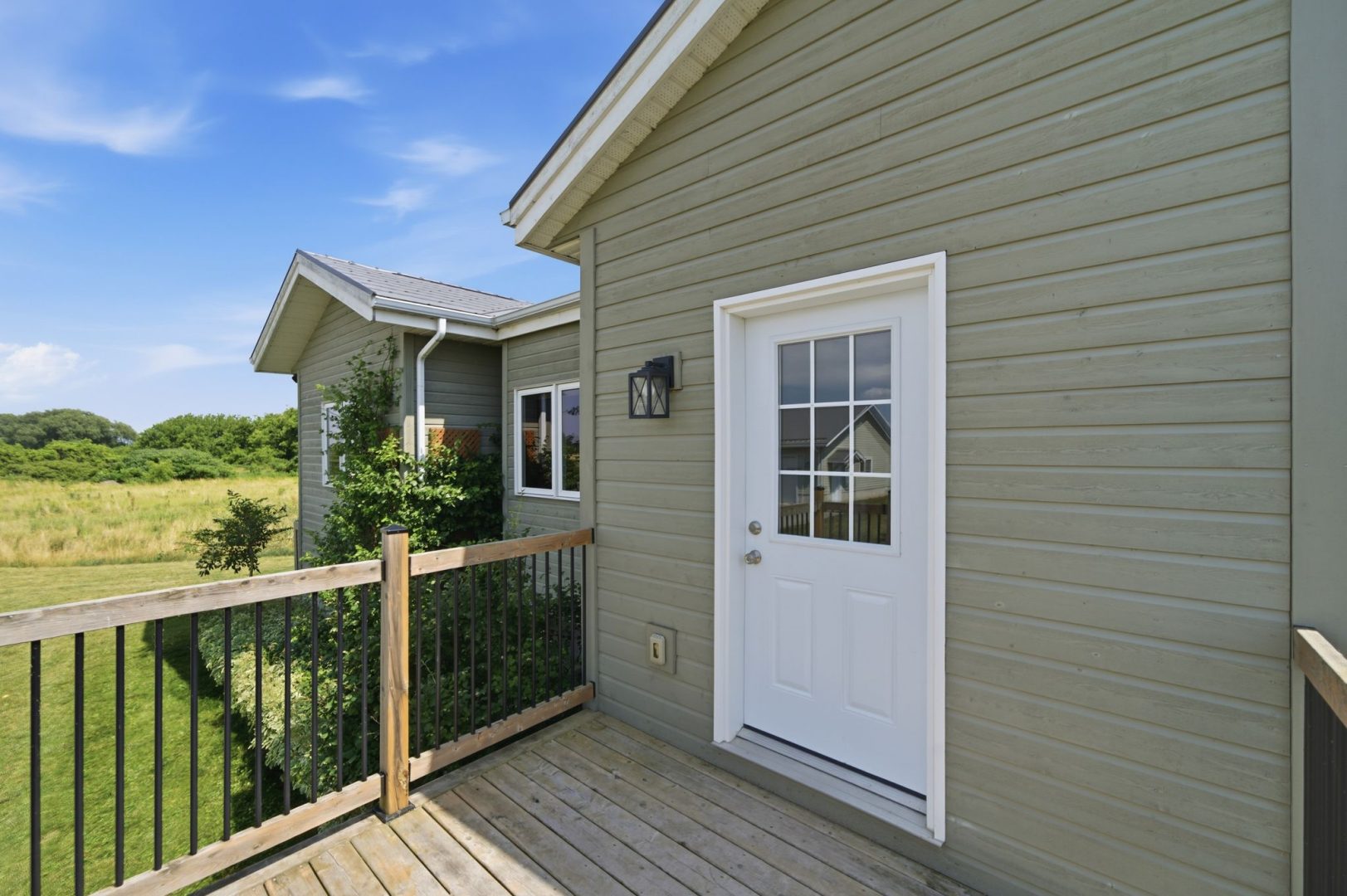 A white front door on a green clapboard cottage