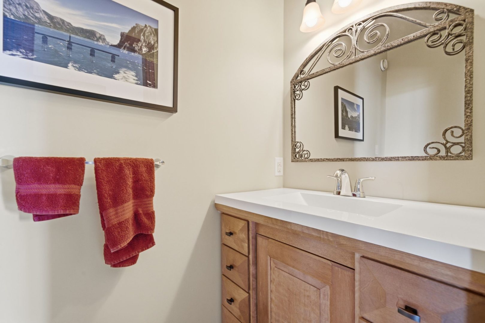 A white bathroom with a wood vanity and a mirror hanging above