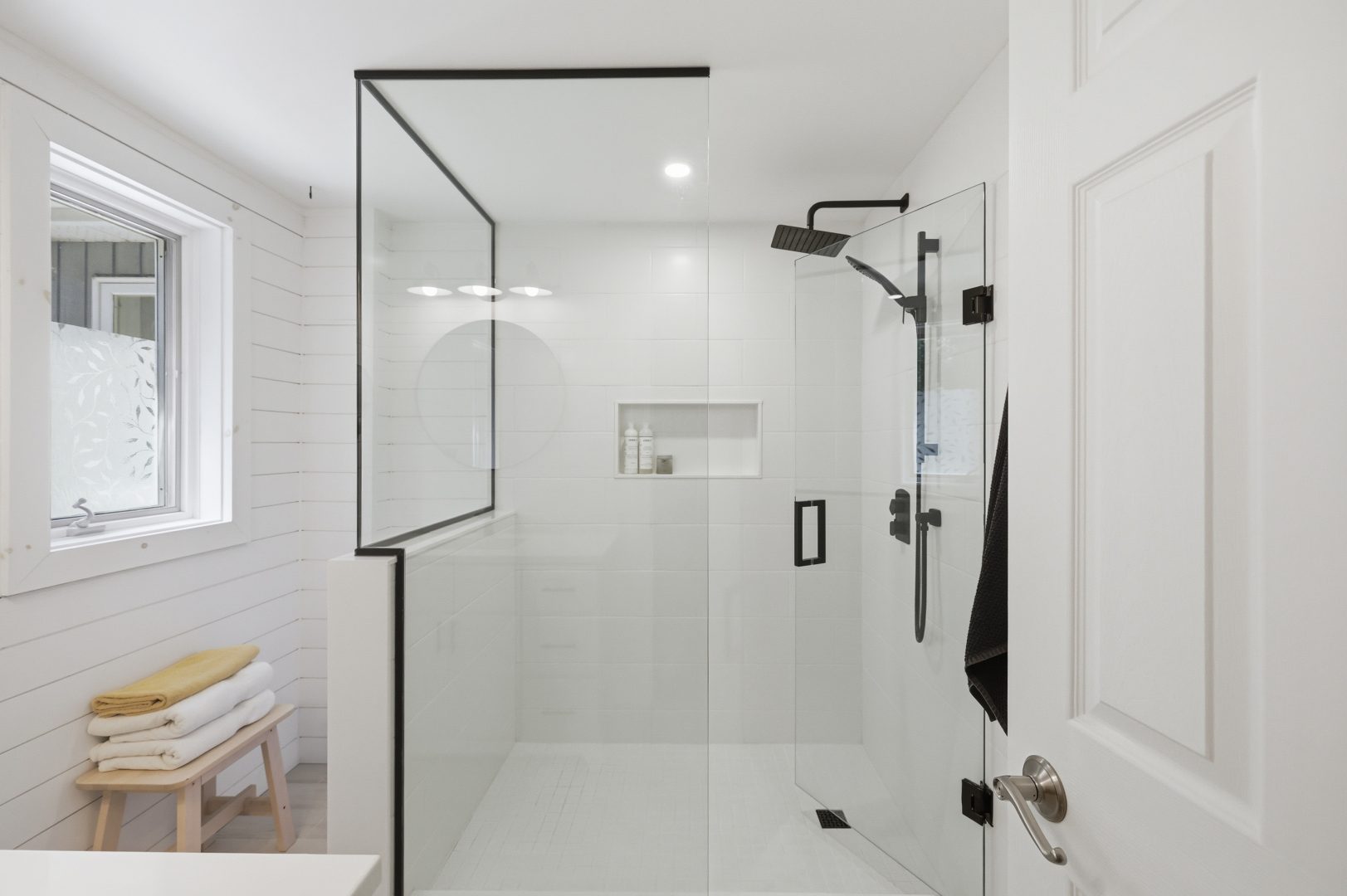 A white tiled walk-in shower with black hardware