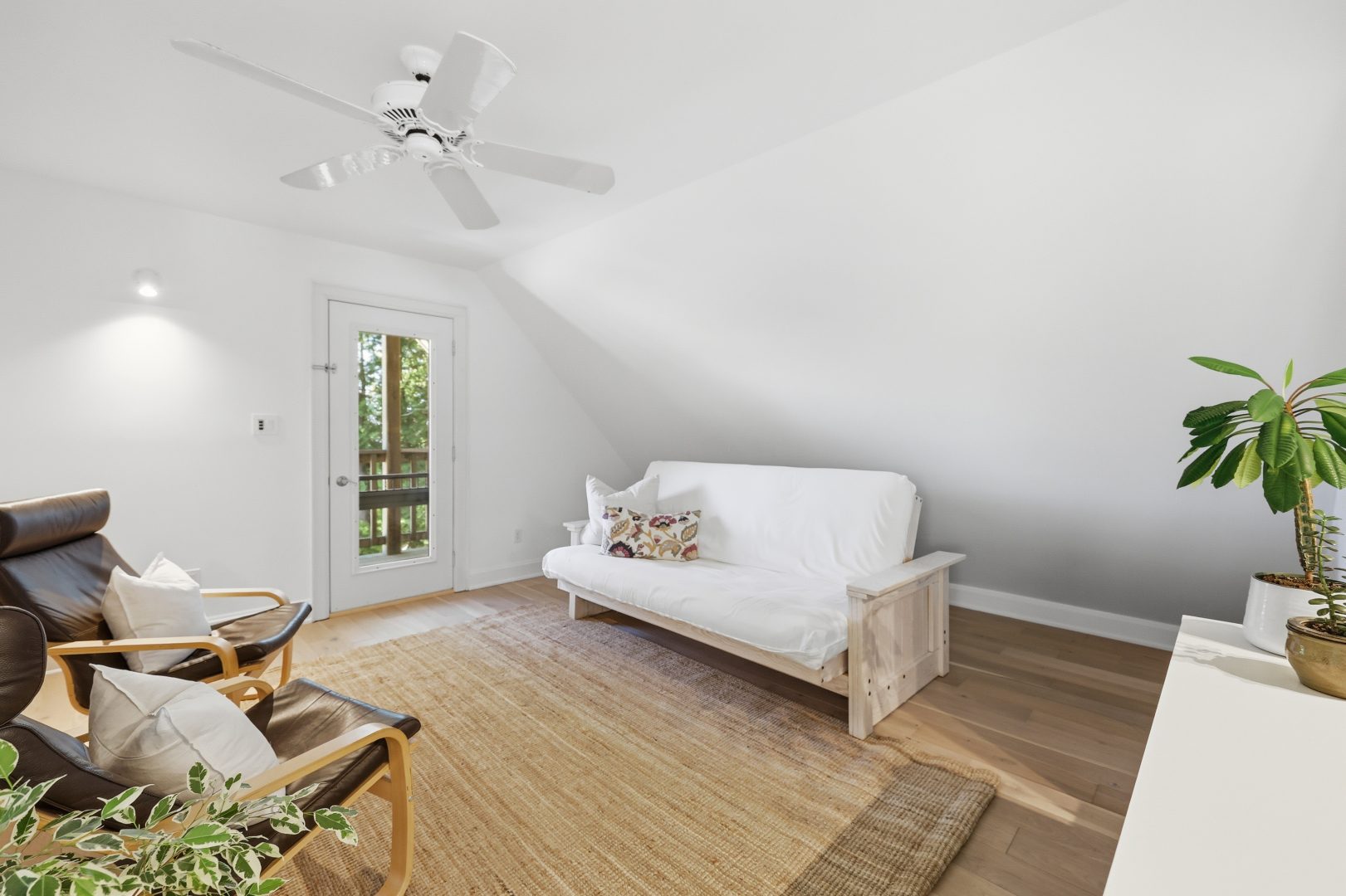 A white loft area with a white couch and grasscloth carpet