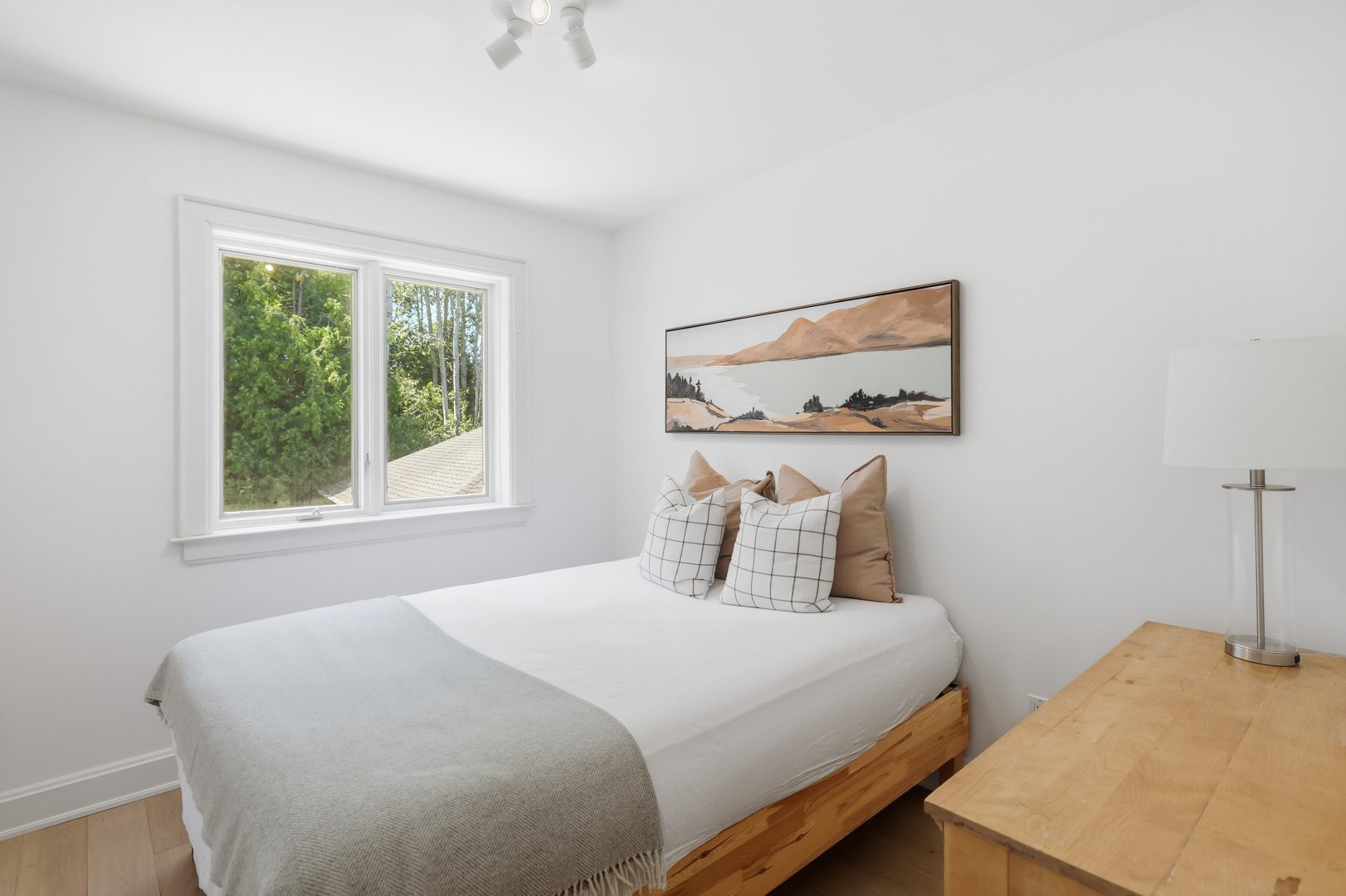 A white bed with a grey blanket in a white bedroom