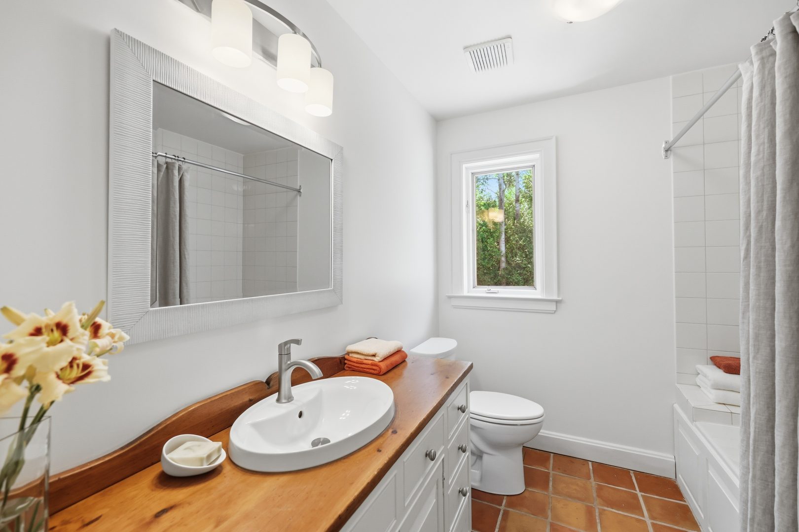 A white bathroom with a wood vanity