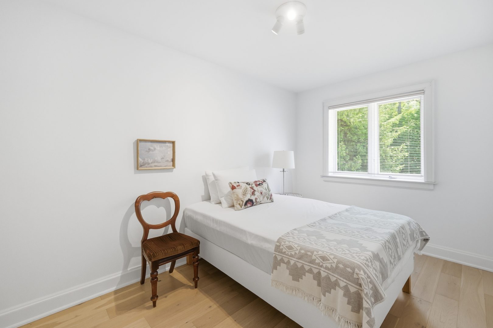 A white bed with a beige blanket in a white room