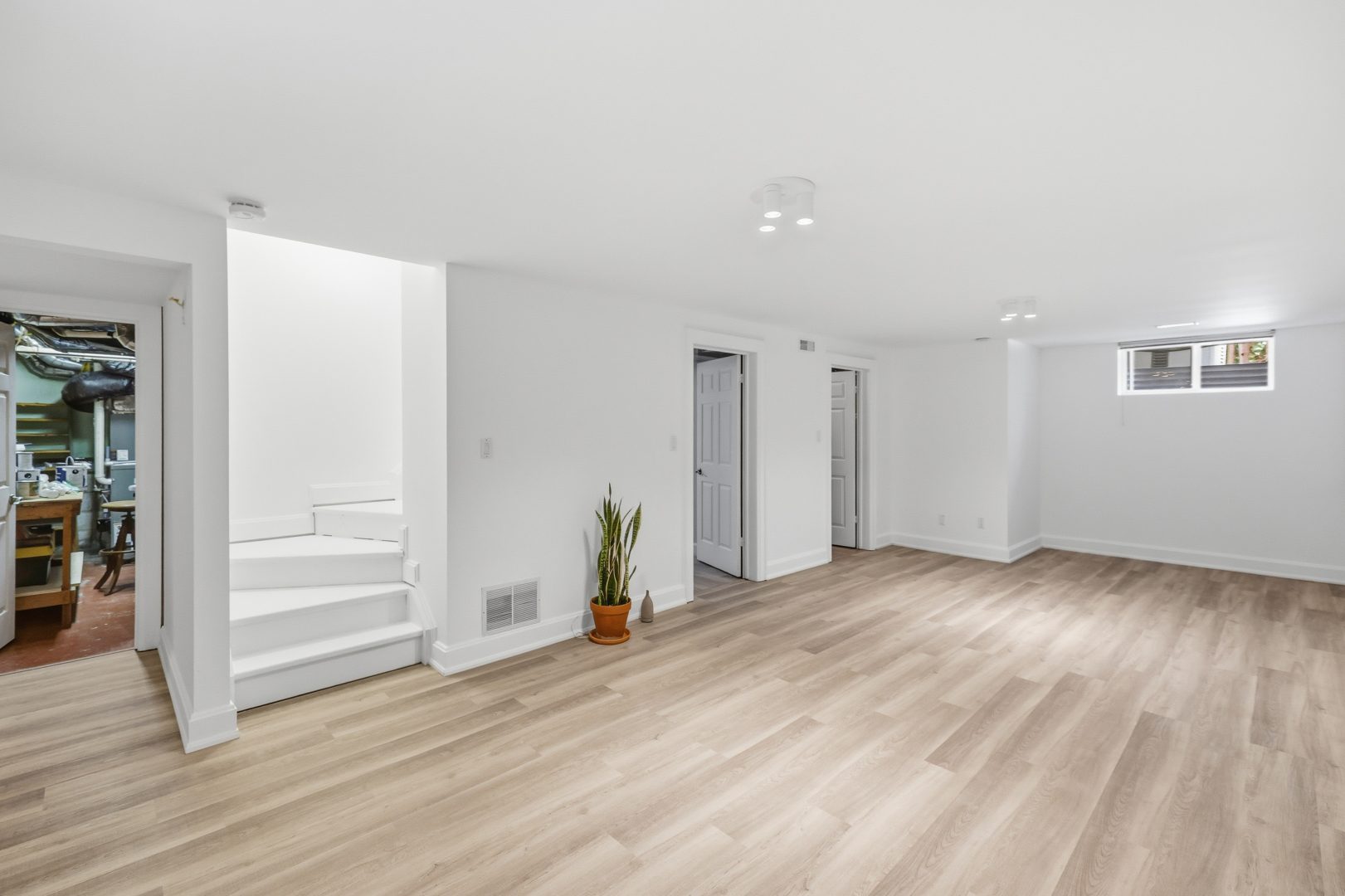 An empty room with light wood floors and white walls
