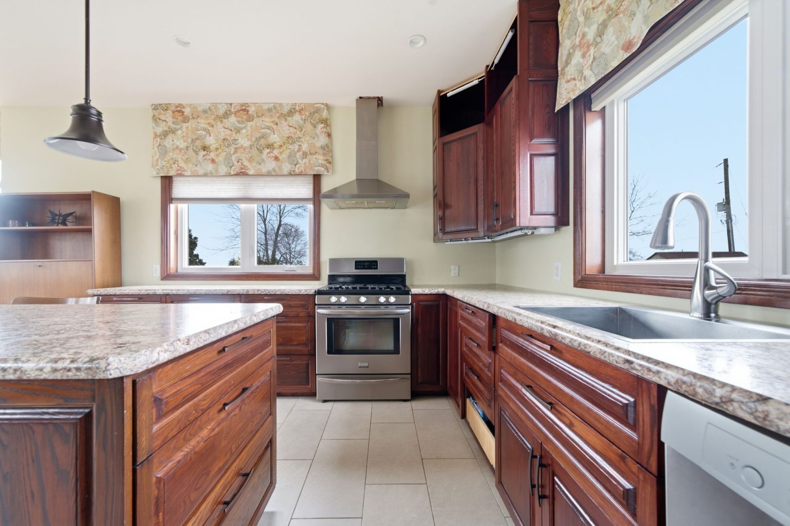 A kitchen with dark wood cabinets and island, and stainless steel appliances.