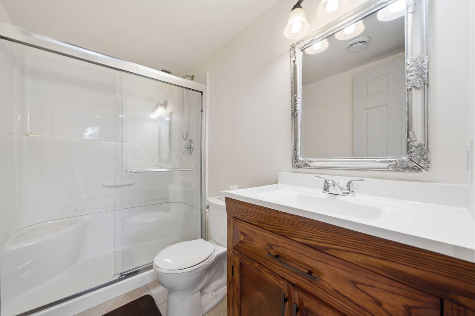 A dark wood vanity in a white bathroom with a glass shower