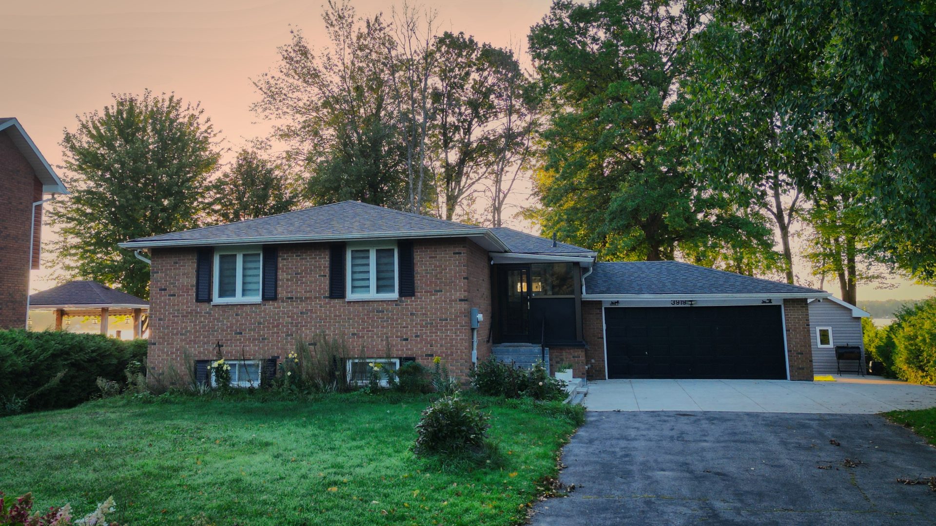 A brick bungalow with black trim and a green lawn