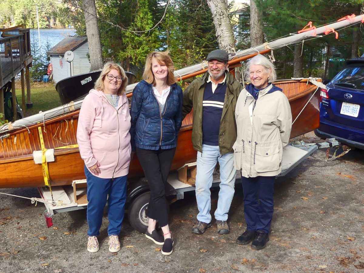 Family standing in front of a sailing dinghie