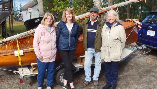 Family standing in front of a sailing dinghie
